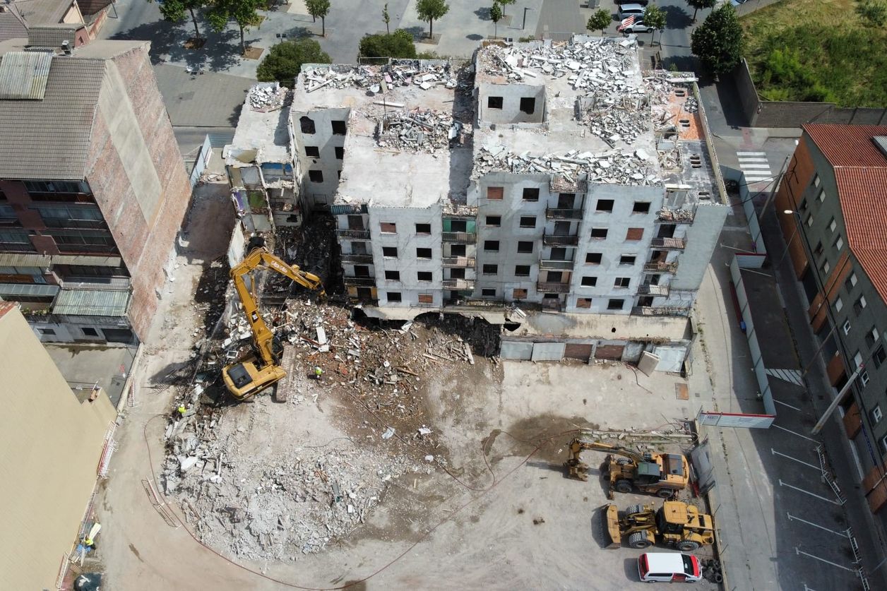 Vista aèria de l’enderroc d’un edifici de pisos amb excavadores treballant entre la runa